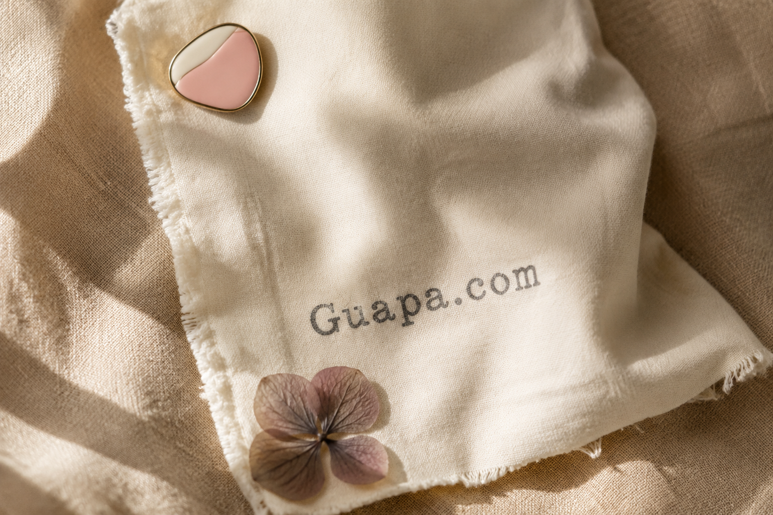 Cream card with the Guapa.com wordmark beside a pressed flower